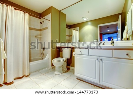 Green and white bathroom with sink and tub with curtain.