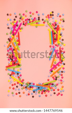 Colorful sprinkles and birthday candles on pink background