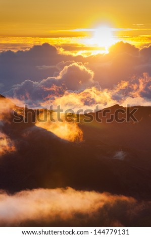 Sun rising over clouds at sunrise from on top of Haleakala Crater, Maui, Hawaii, USA