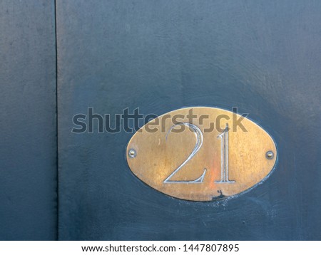 Golden plate with House Number twenty-one on blue door