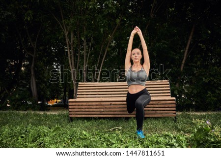 Photo of amazing young sports woman in park outdoors make sport stretching exercises. Young runner stretching before the city race