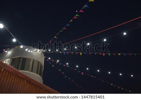 night sky with light bulbs on the wires, round building, window, holiday, dark background