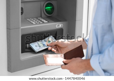 Man taking money from cash machine outdoors, closeup