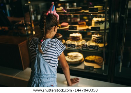 Cute adorable happy girl celebrating birthday and choosing sweets in confectionery. Joyful emotions