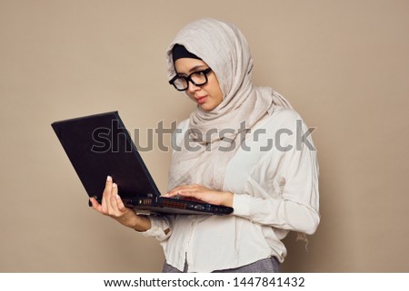  hijab woman with glasses in a veil works behind a laptop                              