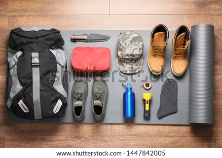 Flat lay composition with different camping equipment on wooden background