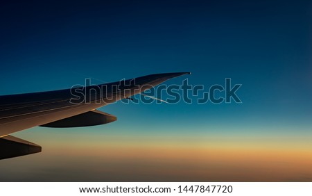 Wing of plane over the city. Airplane flying on blue sky. Scenic view from airplane window. Commercial airline flight in the morning with sunlight. Plane wing above clouds. Flight mechanics concept.