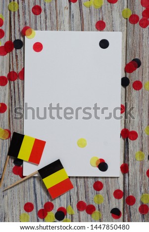national day of Belgium , July 21. national Belgian festival. the concept of celebration, fun, patriotism and freedom. mini flags and confetti with sheets of white paper on white wooden background