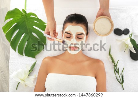 Cosmetologist applying mask on woman's face in spa salon Royalty-Free Stock Photo #1447860299