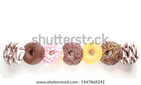 Different donuts with  chocolate frosted, pink glazed and sprinkles on white large background with copy space. Assortment of various colorful donuts. Top view