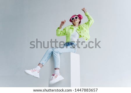 beautiful woman in glasses with hairstyle sitting on a cube