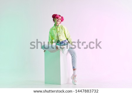 woman with pink hair in jeans sitting on a cube