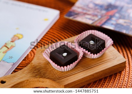 handmade chocolate sweets on a wooden board next to a book and a picture