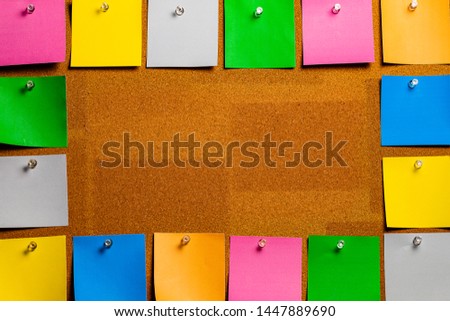 Corkboard/Bulletin Board bordered completely by very orderly placed multicolored sticky type square notes.  The notes are all blank and easily edited with copy and the center is open for copywriting.