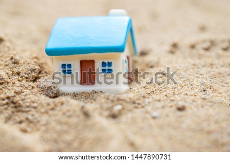 a small house with a blue roof in a sandy landscape