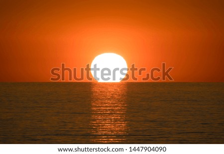 Close-up of beautiful orange sunset and sun setting in ocean