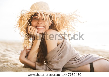 Image of young cheery happy smiling gorgeous attractive woman lies outdoors at the sea beach.