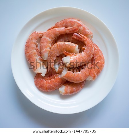 Royal prawns on a white plate. Cooked, defrosted semi-finished product. Top view