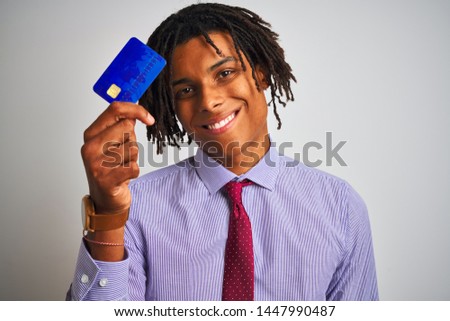 Afro american businessman with dreadlocks holding credit card over isolated white background with a happy face standing and smiling with a confident smile showing teeth