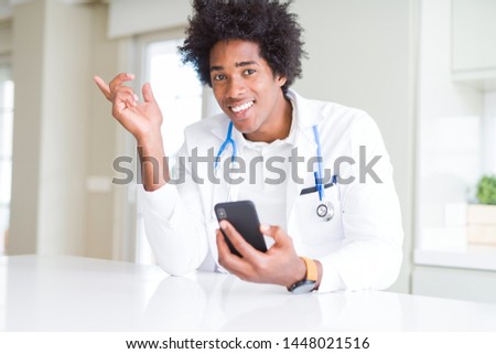 African American doctor man using smartphone at the clinic very happy pointing with hand and finger to the side