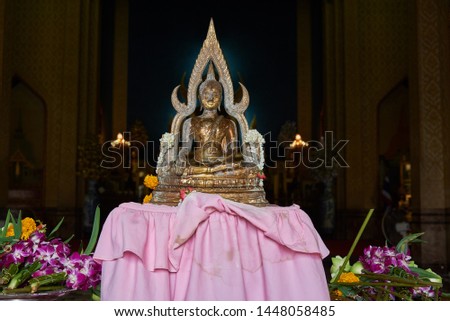 A buddhist statue in meditation at the marble temple or wat Benjamaborphit and sacred flowers