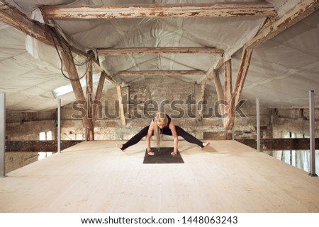 Strong. A young athletic woman exercises yoga on an abandoned construction building. Mental and physical health balance. Concept of healthy lifestyle, sport, activity, weight loss, concentration.