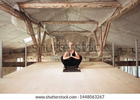 Power. A young athletic woman exercises yoga on an abandoned construction building. Mental and physical health balance. Concept of healthy lifestyle, sport, activity, weight loss, concentration.