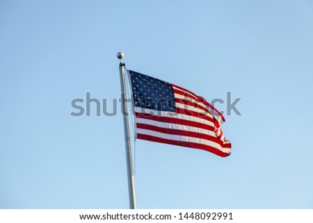 Flag of the United States of America, photograph in the wind, consists of 7 red bands and 6 white bands and a blue rectangle with 50 stars, symbolizing the states of the country.