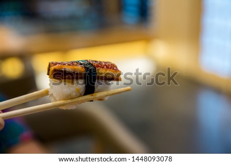 Close up chopsticks hold on sushi freshwater eel grilled. Japanese food for healthy. unagi sushi, premium sushi menu. image for background,wallpaper, copy space and menu list.