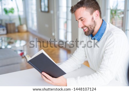 Handsome man reading a book at home