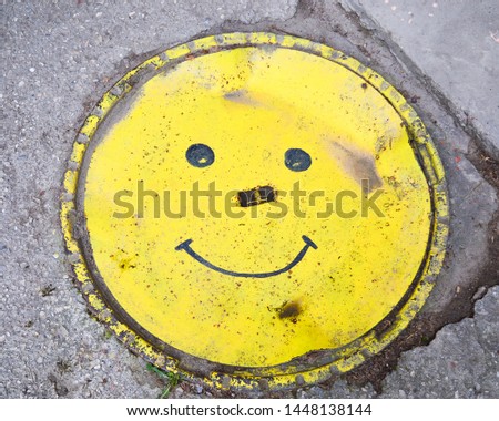 Decorative manhole in the form of a yellow smile. The concept of urban design.