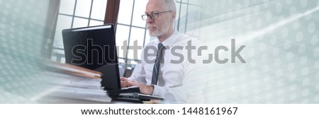 Senior businessman working on laptop in office; panoramic banner