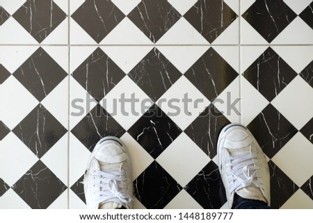 Checkered patterned floor with white sneakers