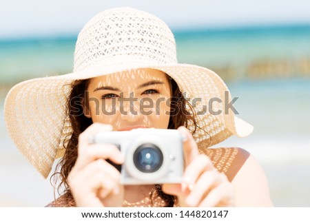 Attractive cheerful summer woman talking pictures with digital camera .
