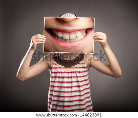 little girl holding a picture of a mouth smiling