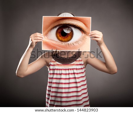 little girl holding a picture of an eye watching