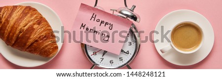 top view of alarm clock with happy morning lettering on sticky note near coffee and croissant on pink background, panoramic shot
