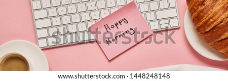 top view of computer keyboard and pink sticky note with happy morning lettering near croissant and coffee on pink background, panoramic shot