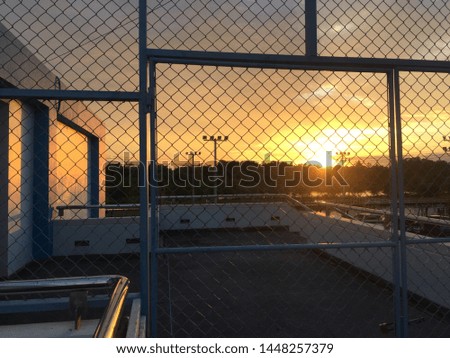 Shadow metal net fence on the sunset orange sky.
