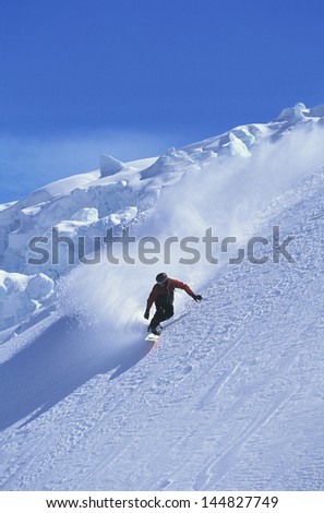 Snowboarder snowboarding on steep slope