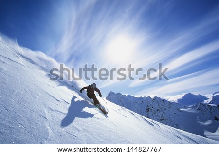 Full length of skier skiing on fresh powder snow Royalty-Free Stock Photo #144827767