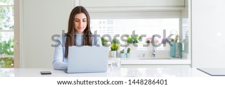 Wide angle picture of beautiful young woman working or studying using laptop with a confident expression on smart face thinking serious Royalty-Free Stock Photo #1448286401