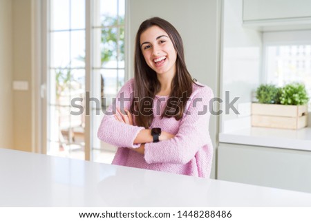 Beautiful young woman wearing pink sweater happy face smiling with crossed arms looking at the camera. Positive person.