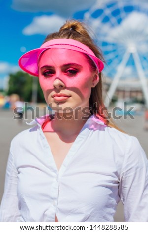 Portrait of an emotional beautiful young girl in a pink cap visor and protective gloves for rollerblades and skateboarding.