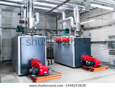 Large central heating / oil heating in a large hall, with two red fans. Royalty-Free Stock Photo #1448293838