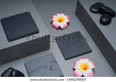 Aromatherapy and wellness spa concept. Black zen river stones, frangipani on grey and black set.