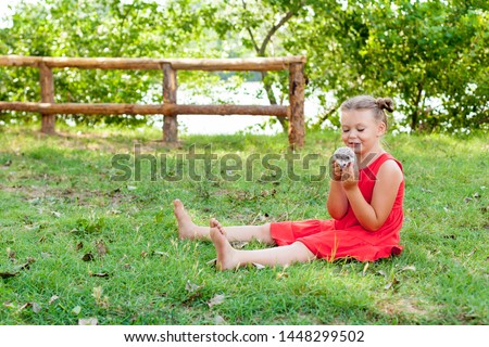 happy little girl playing with her pet African pygmy hedgehog. Children and pets. three little girls sit on the grass and play with a wild animal. Preschooler watching animals outdoors in summer.