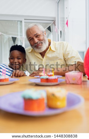 Front view of African-American boy birthday. He taking a picture with his grandfather. Authentic Senior Retired Life Concept