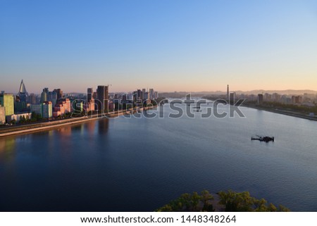 Pyongyang, DPR Korea North Korea and Taedong River in the morning fog. View facing upstream, modern residential complex, Taedong bridge and Juche Tower from the Yanggakdo island Royalty-Free Stock Photo #1448348264