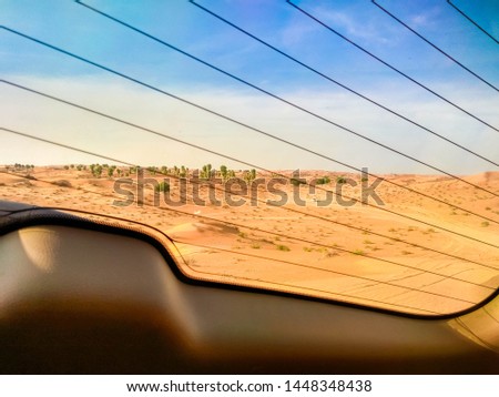 Off-road safari on SUVs in the Arab orange-red sands desert in the sunset sun. The picture from the inside of the car. On background the desert and rare bushes. The car costs at top of sandy dunes